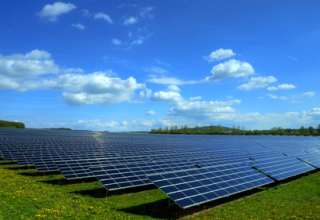 Solarkraftwerk auf satter Wiese bei schönem Wetter