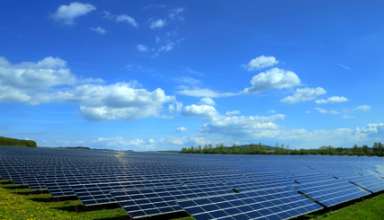 Solarkraftwerk auf satter Wiese bei schönem Wetter