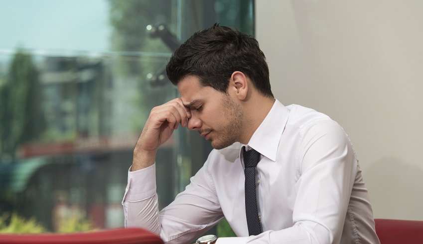 Junger Mann sitzt gestresst im Büro